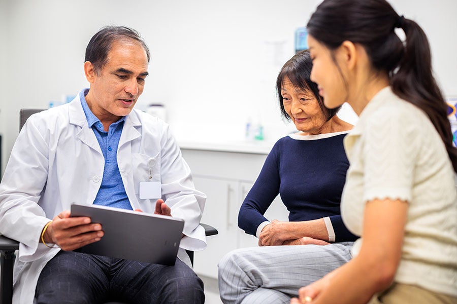 Doctor speaking with patients and referring to notebook.