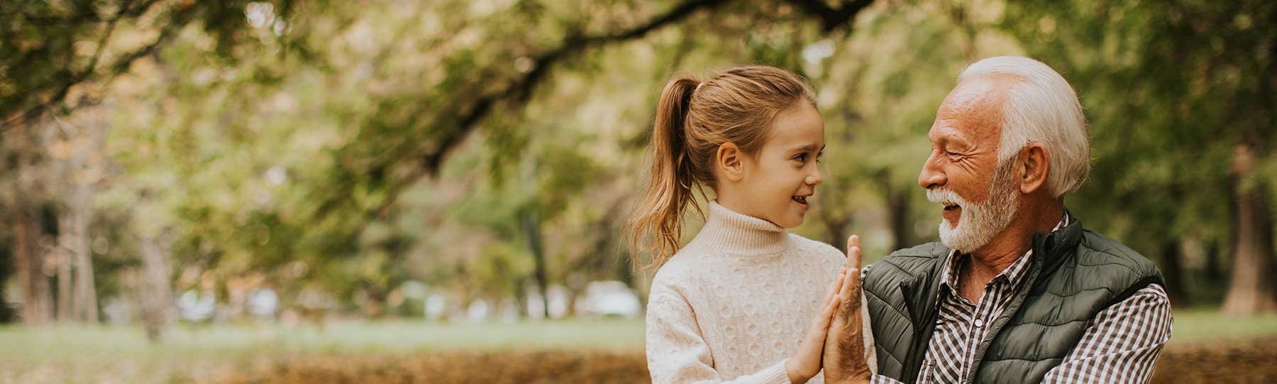 Child high-fiving an older person outdoors.
