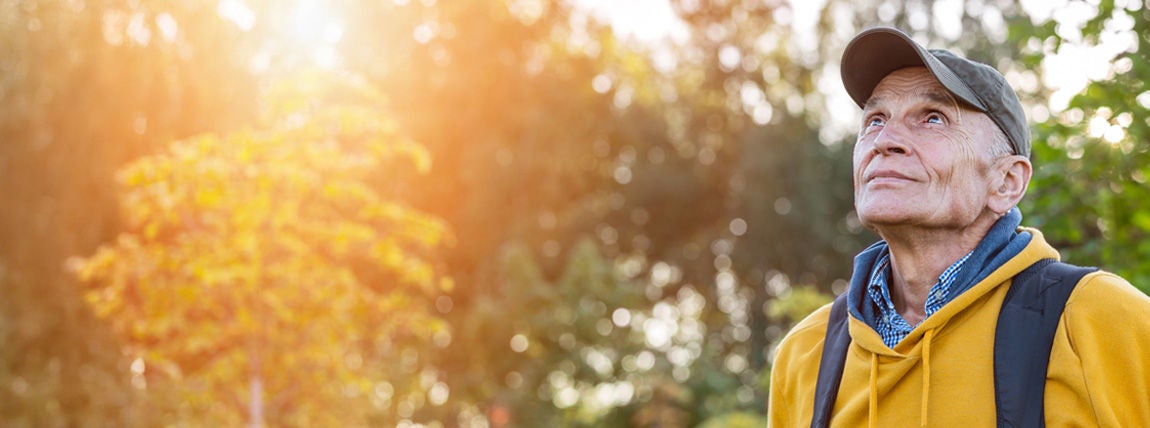 Older man outdoors wearing a yellow jacket.
