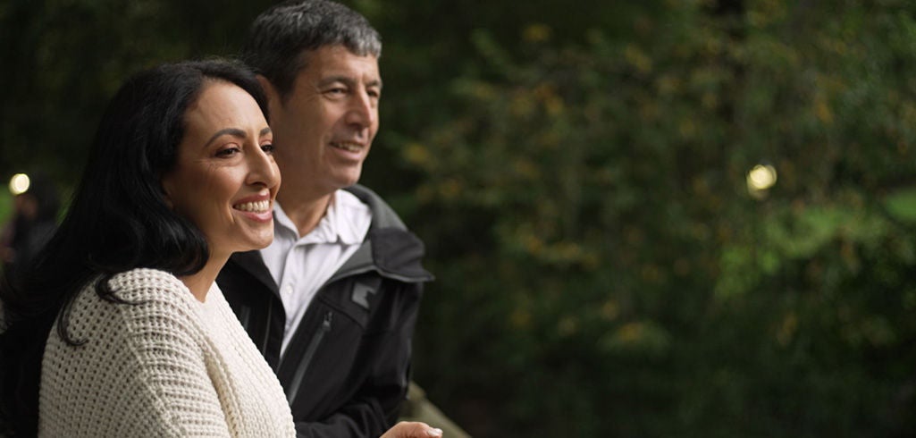 Couple standing next to a bridge.